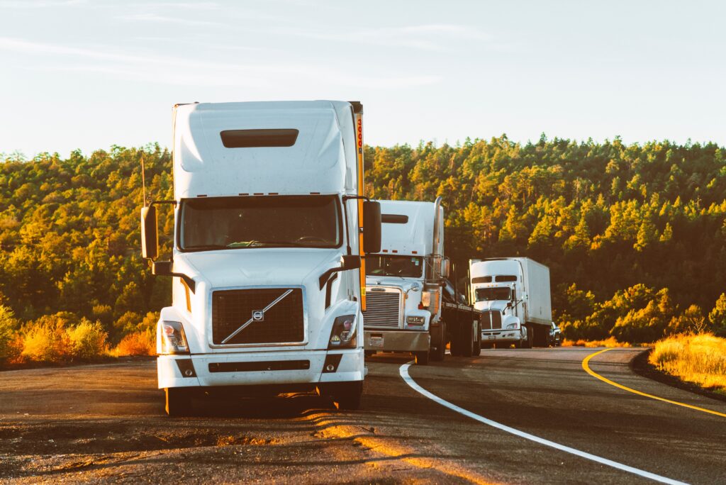 white Volvo semi-truck driving on a highway, with other trucks in the background